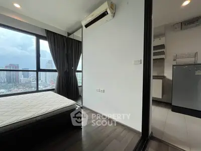 Modern high-rise apartment with city view, featuring a cozy bedroom and sleek kitchen area.