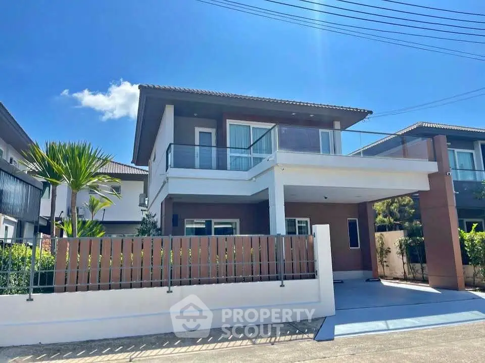 Modern two-story house with balcony and spacious driveway in sunny neighborhood.