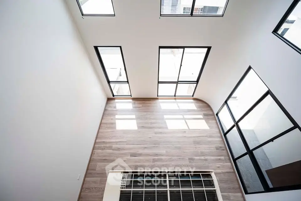 Spacious modern interior with large windows and sleek wooden flooring, perfect for natural light lovers.