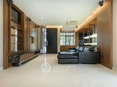Luxurious modern living room with sleek black leather sofa and elegant wooden accents.