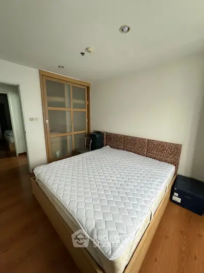 Spacious bedroom with wooden flooring and large bed in modern apartment.