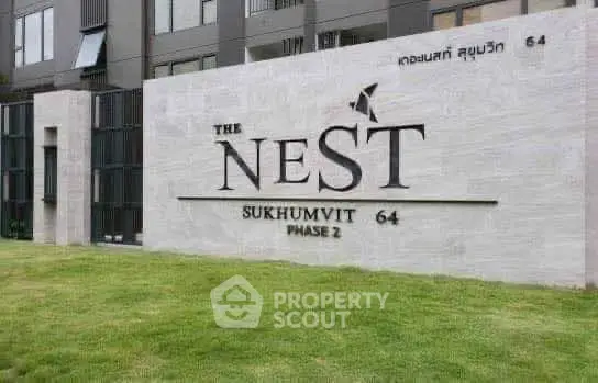 Modern building exterior with The Nest Sukhumvit 64 Phase 2 signage on a stylish stone wall.