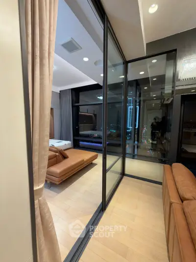 Luxurious modern apartment with glass walls and leather seating, offering a stunning city view.
