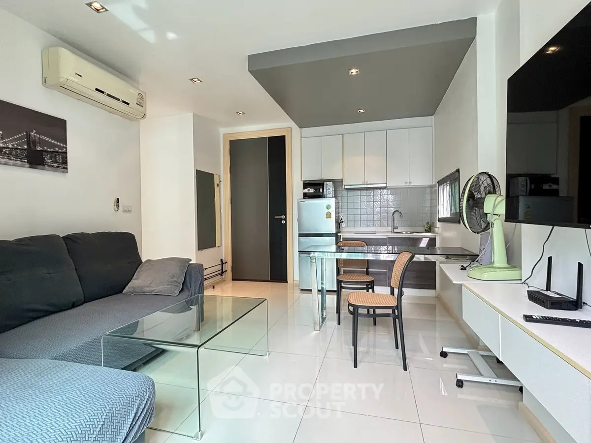 Modern living room with open kitchen, sleek furniture, and air conditioning in a stylish apartment.