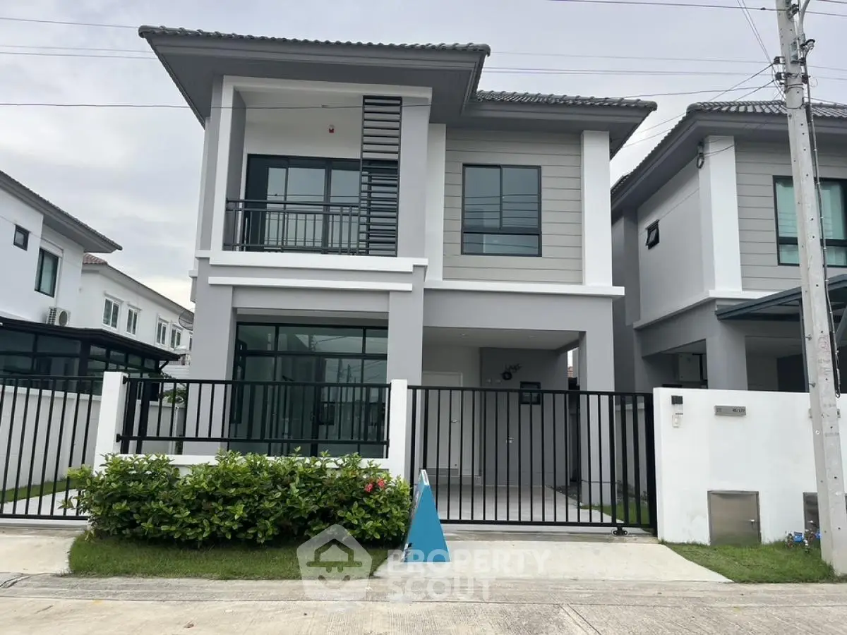 Modern two-story house with sleek design and gated entrance in suburban neighborhood.