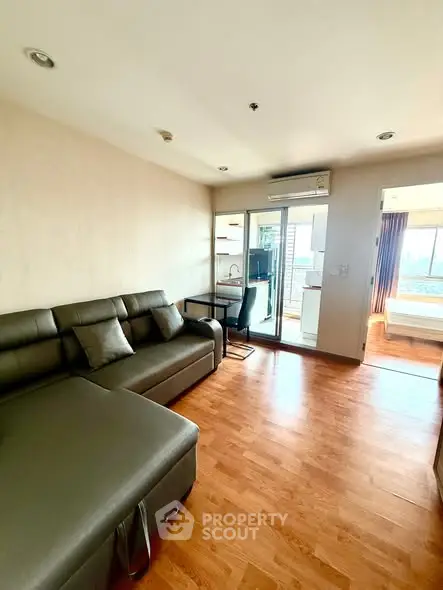 Modern living room with sleek furniture and open layout leading to a bright bedroom with a view.