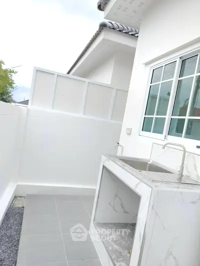Modern outdoor kitchen area with sleek marble countertops and stainless steel sink.