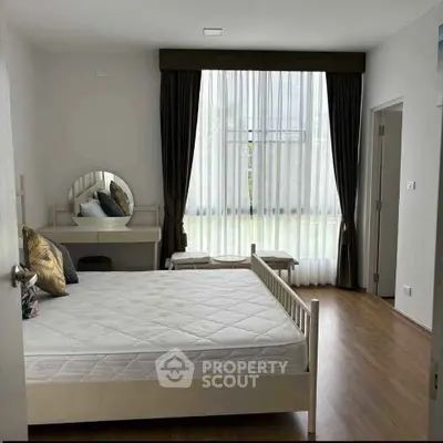 Spacious bedroom with large window and elegant decor in modern apartment.