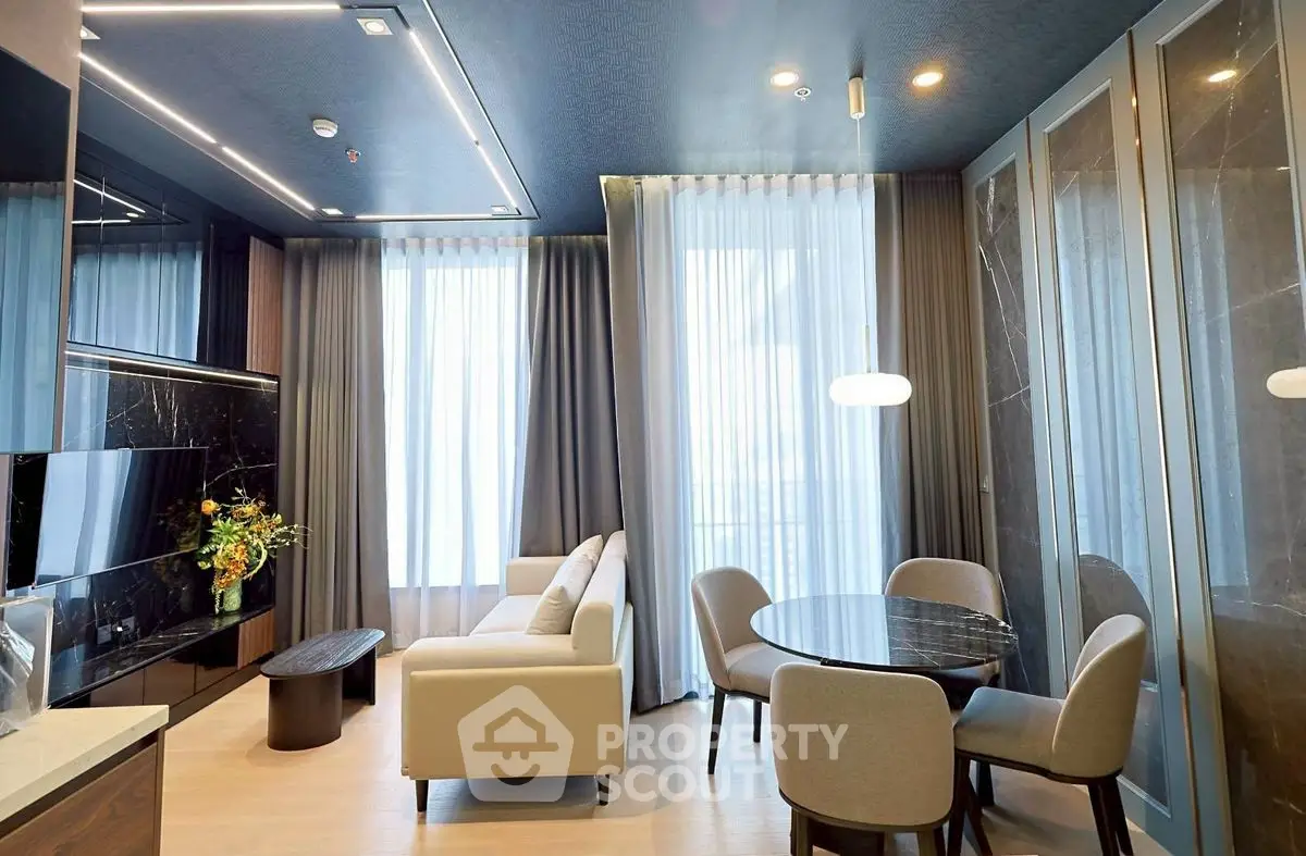 Modern living room with elegant decor and dining area, featuring floor-to-ceiling windows and stylish furniture.