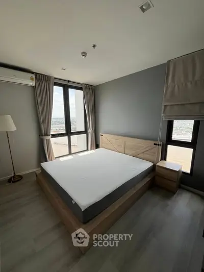 Modern bedroom with large windows and stylish decor in a high-rise apartment.