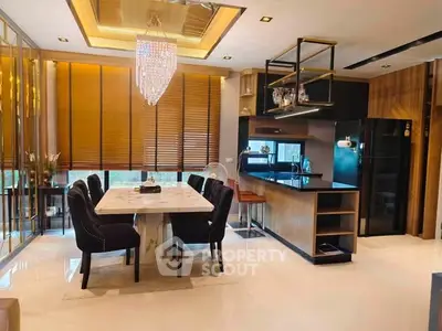 Luxurious modern kitchen and dining area with elegant chandelier and sleek design.