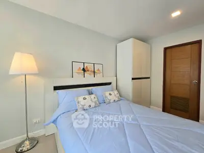 Cozy bedroom with modern decor and ample natural light, featuring a stylish bed and wardrobe.