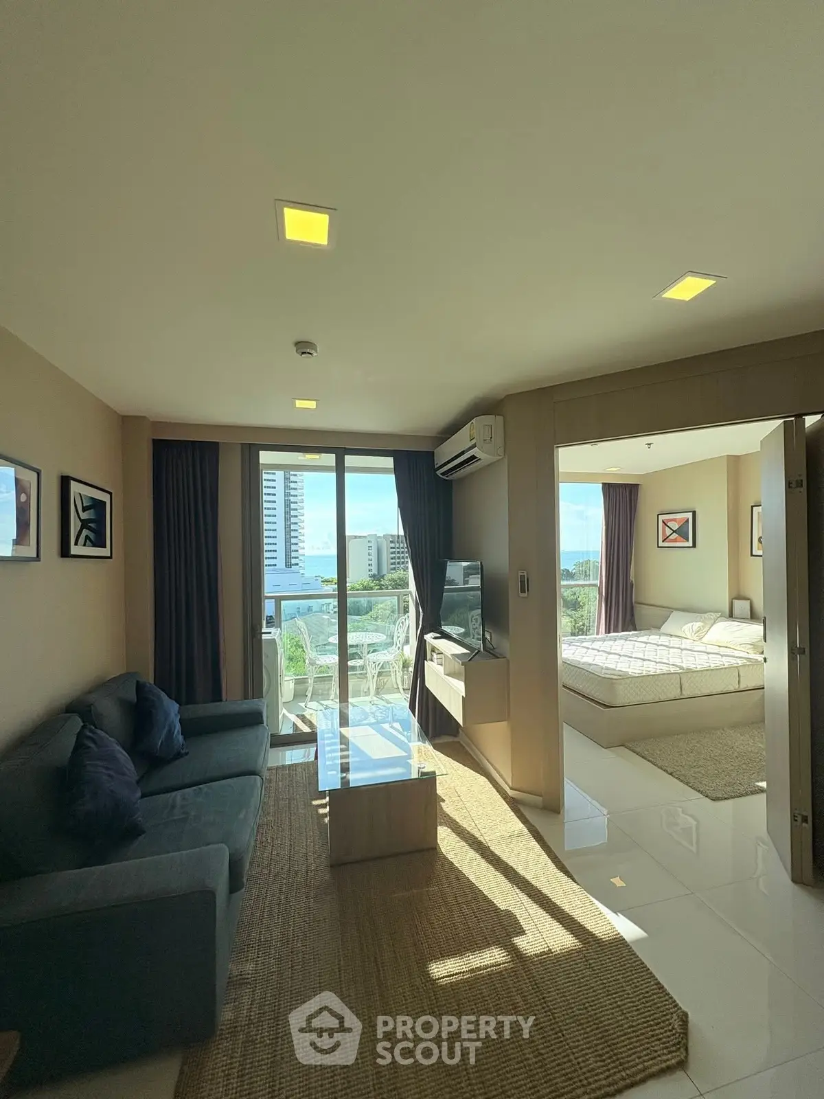 Modern living room with natural light and city view, adjacent to cozy bedroom.