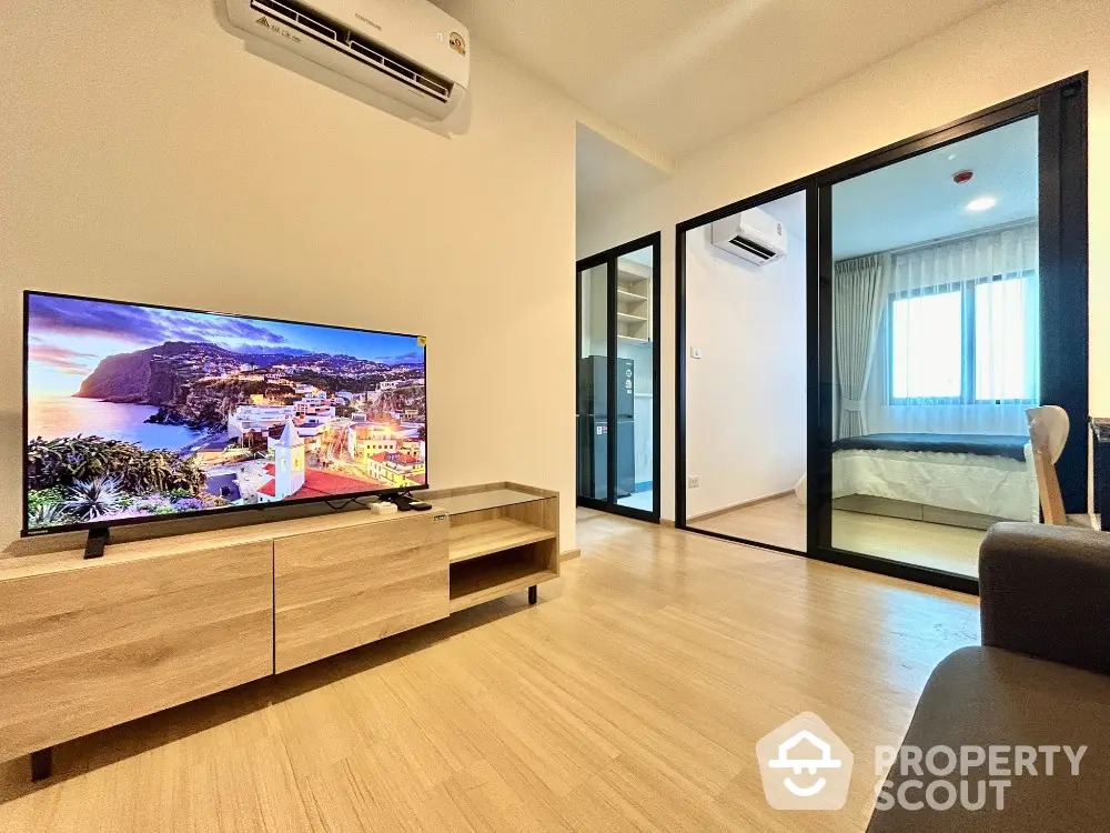 Modern living room with TV and view into cozy bedroom