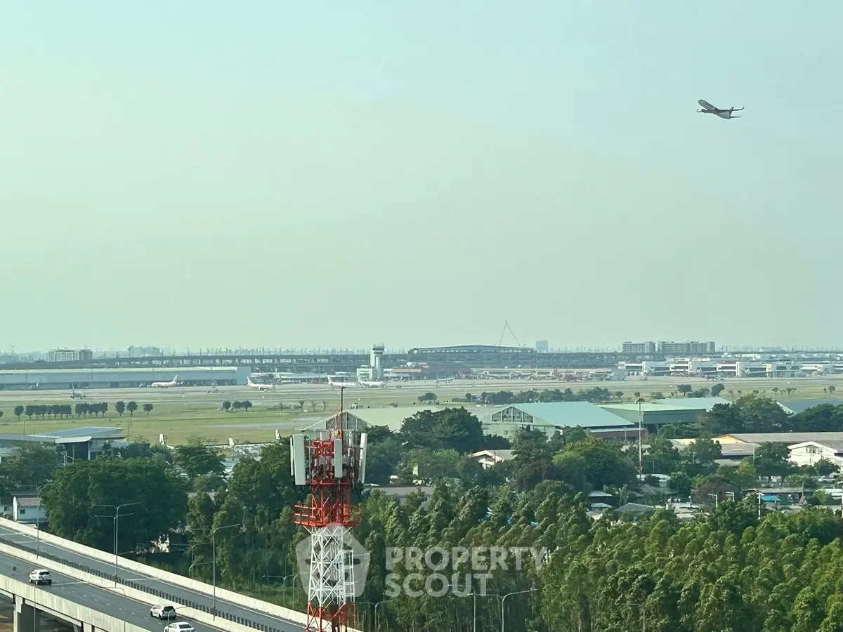 Stunning aerial view of airport with airplane taking off, showcasing expansive runway and surrounding landscape.