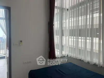 Modern bedroom with large windows and balcony access in urban apartment