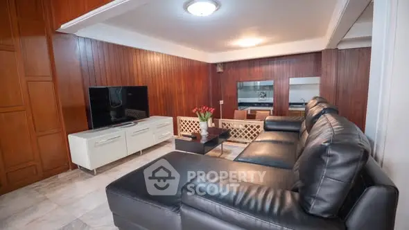 Spacious living room with modern leather sofa and wooden paneling, perfect for relaxation and entertainment.