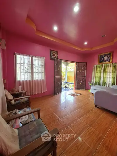 Vibrant living room with pink ceiling and open doors to a sunny balcony
