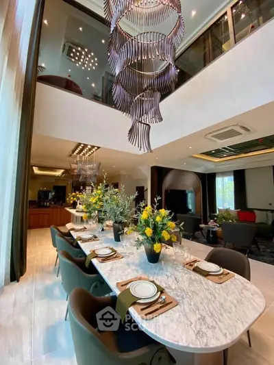 Luxurious dining area with elegant chandelier and modern decor in a spacious open-plan living room.