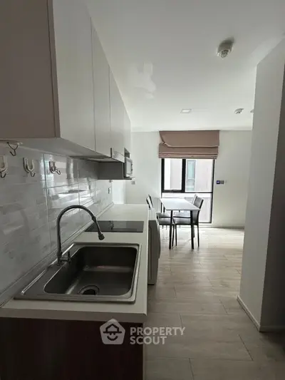 Modern kitchen with sleek cabinetry and dining area in a contemporary apartment.