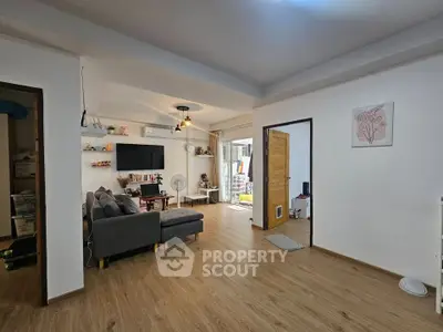 Spacious living room with modern decor and open layout, featuring a cozy sofa and stylish lighting.