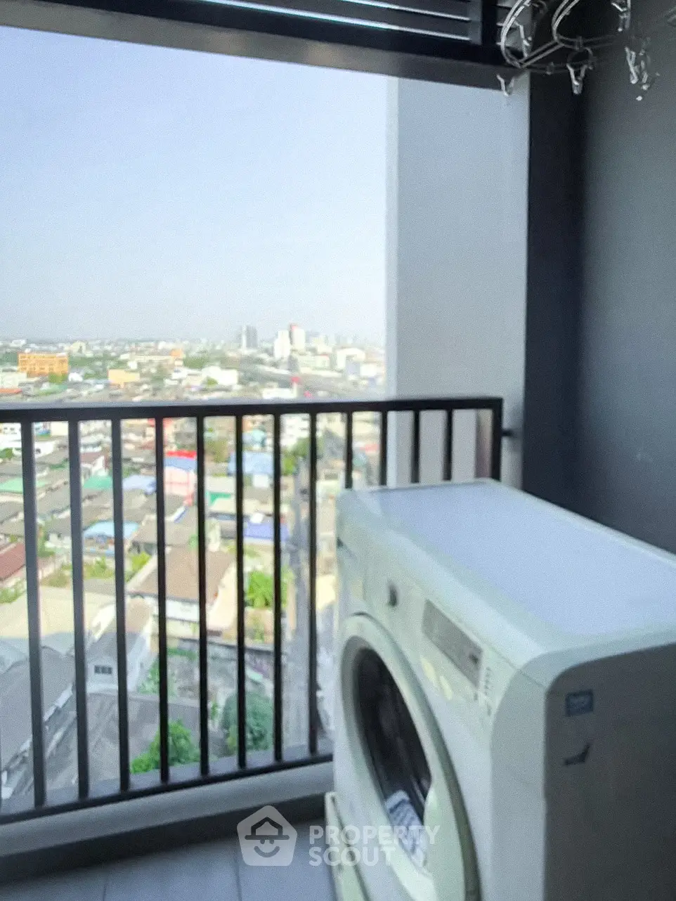 High-rise balcony with washing machine and panoramic city view, perfect for urban living.