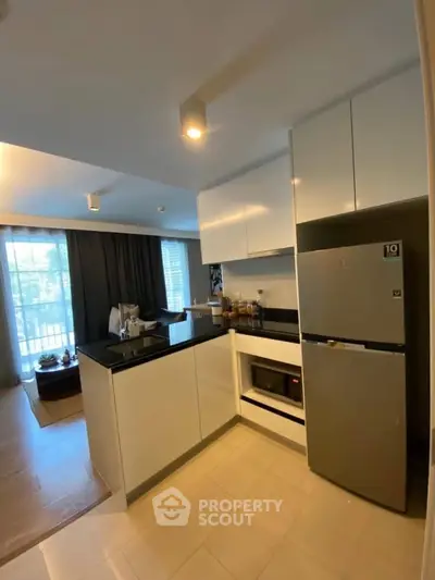 Modern kitchen with sleek cabinets and stainless steel appliances in open layout apartment.