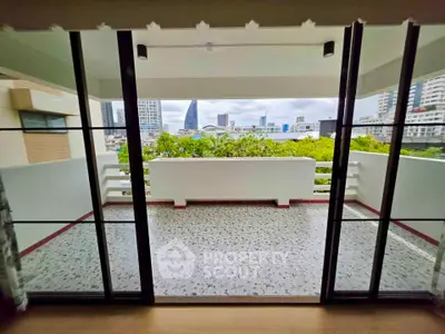 Spacious balcony with city view and modern glass doors in urban apartment