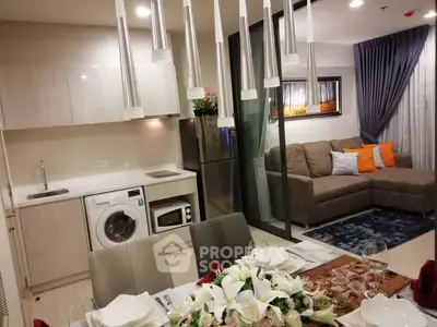 Modern open-plan kitchen and living room with washing machine and cozy seating area.