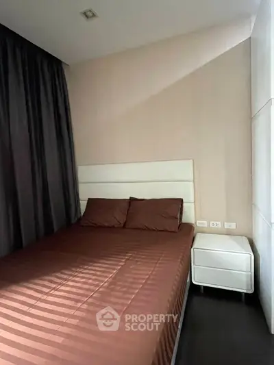 Cozy bedroom with modern design featuring a comfortable bed and sleek nightstand, perfect for relaxation.