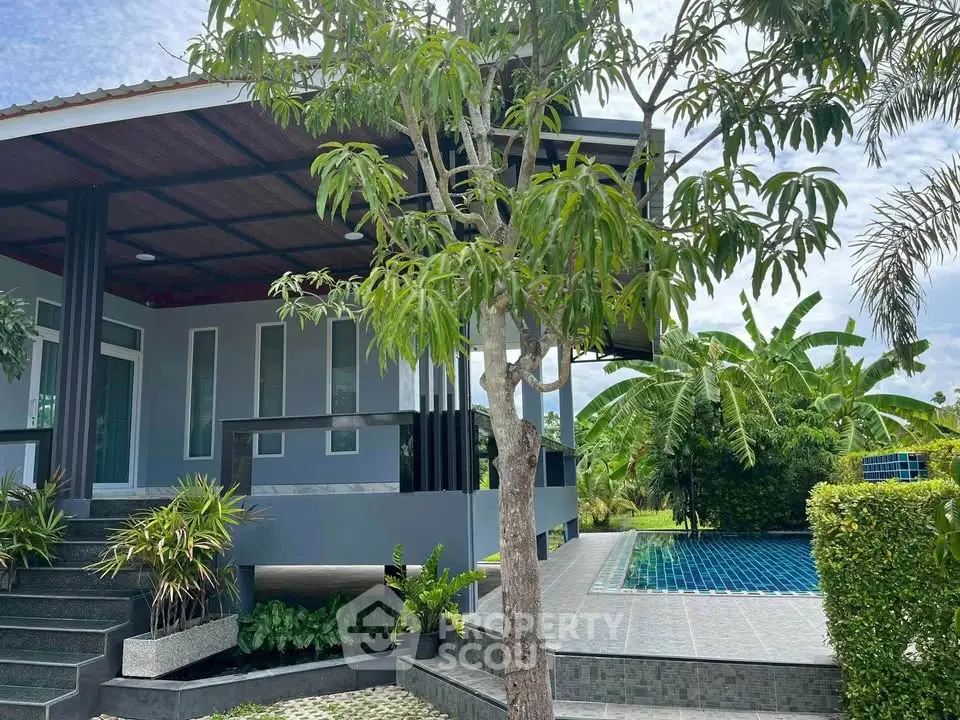 Modern house with lush garden and inviting pool, perfect for relaxation and outdoor enjoyment.