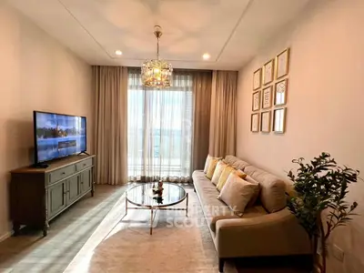Elegant living room with modern decor, large TV, and natural light from floor-to-ceiling windows.