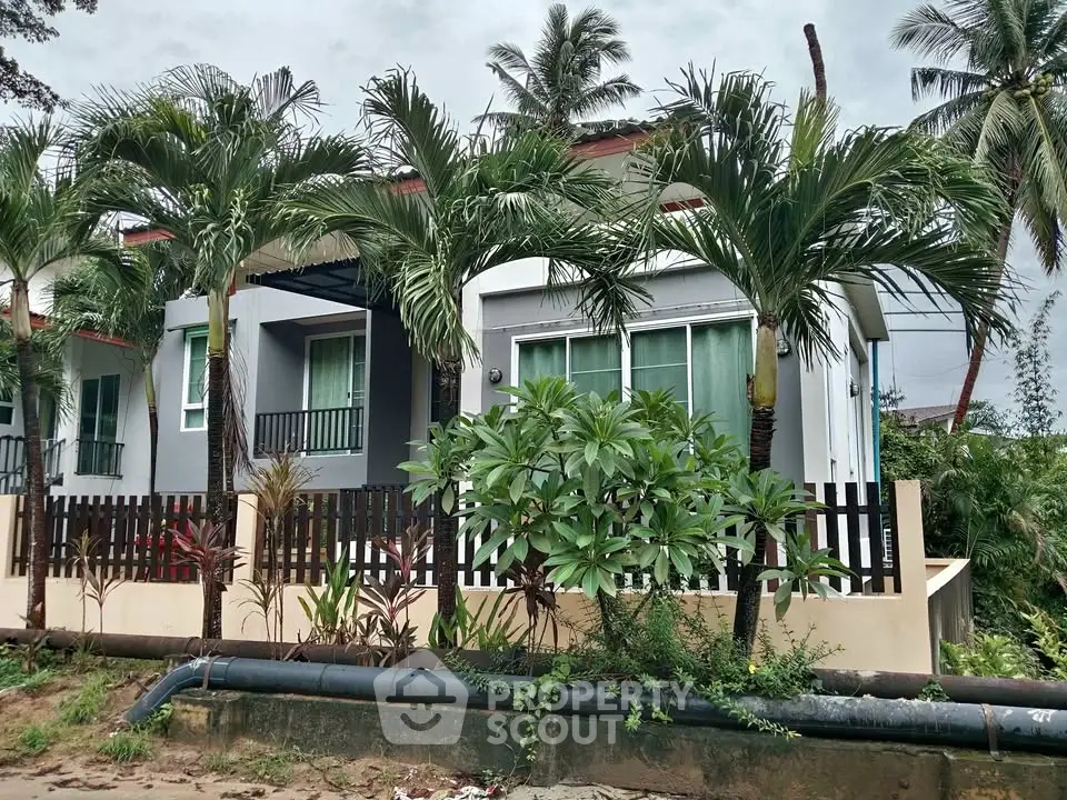 Charming tropical-style house with lush greenery and modern design, perfect for serene living.