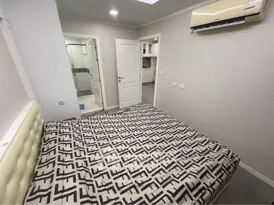 Modern bedroom with stylish decor and air conditioning, featuring a view into a sleek kitchen area.