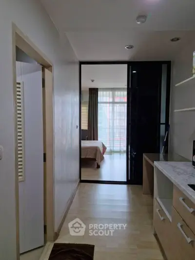 Modern apartment hallway leading to a cozy bedroom with natural light