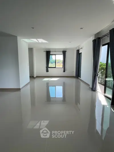 Spacious and bright living room with large windows and glossy floors