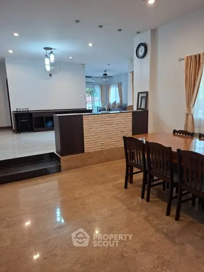 Spacious open-plan living and dining area with elegant wooden furniture and natural light.