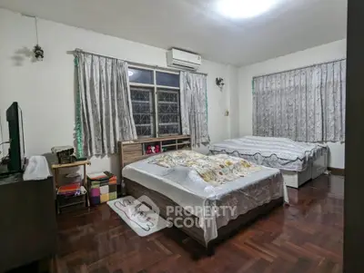 Spacious bedroom with two beds and wooden flooring, perfect for a cozy family setup.