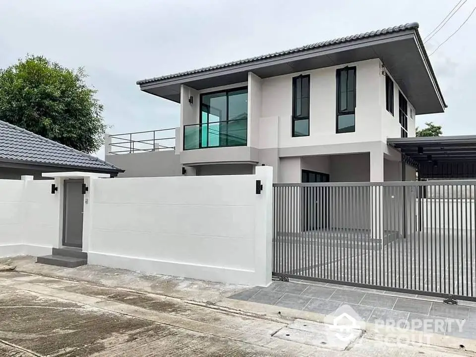 Modern two-story house with sleek design and spacious driveway in suburban setting.