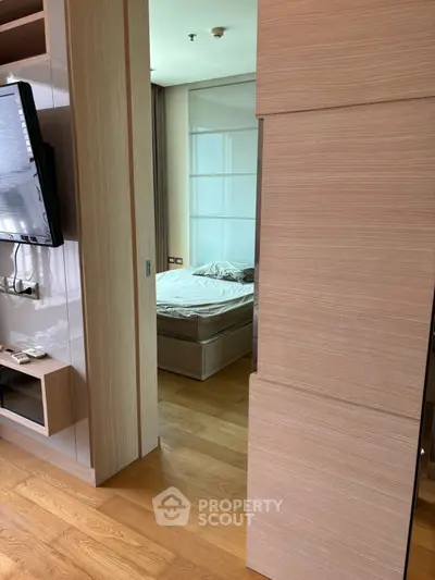 Modern bedroom with wooden flooring and wall-mounted TV in a stylish apartment.