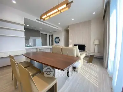 Modern living room with open kitchen, stylish furniture, and ample natural light.