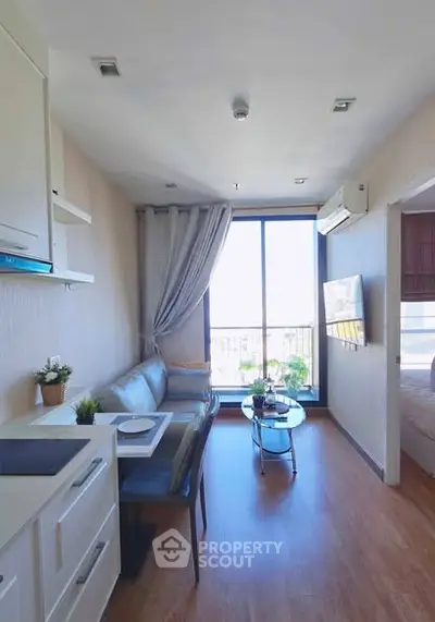 Modern living room with sleek furniture and large window offering natural light.