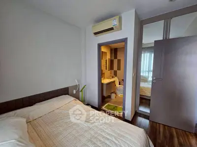 Cozy bedroom with ensuite bathroom and mirrored closet in modern apartment.