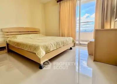 Spacious bedroom with balcony offering stunning city views and abundant natural light.