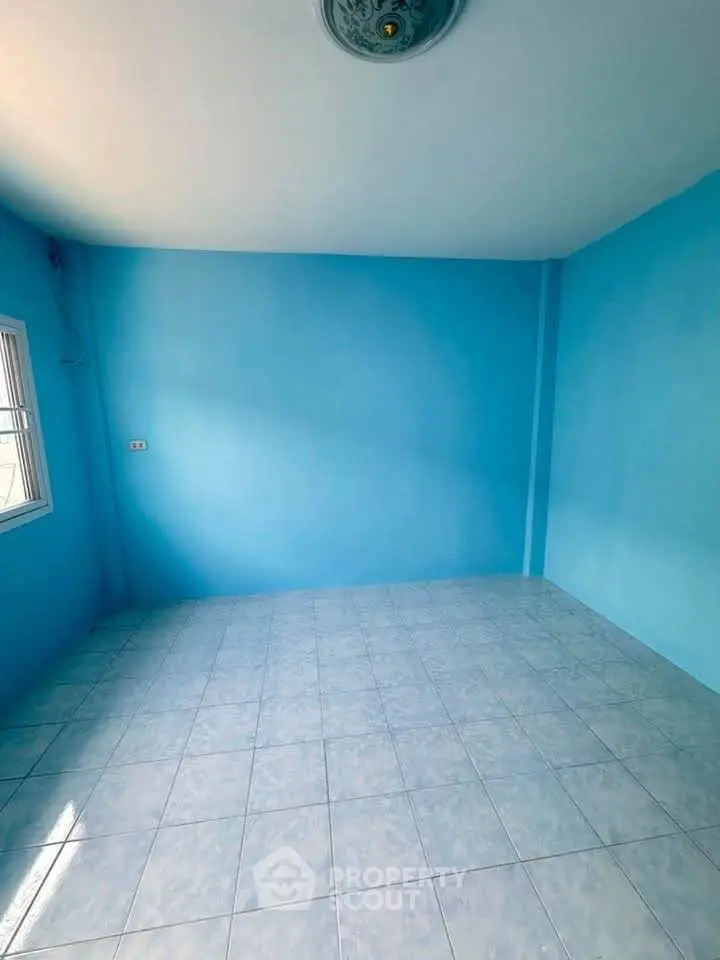 Spacious empty room with vibrant blue walls and tiled flooring, perfect for customization.