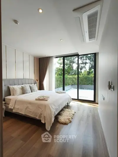 Luxurious bedroom with large windows and garden view, featuring elegant decor and cozy ambiance.