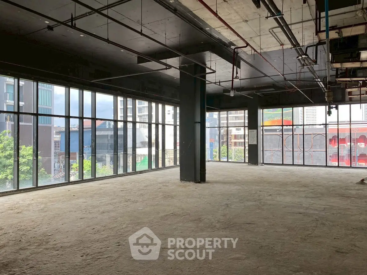 Spacious commercial space with floor-to-ceiling windows offering city views, ideal for office or retail setup.