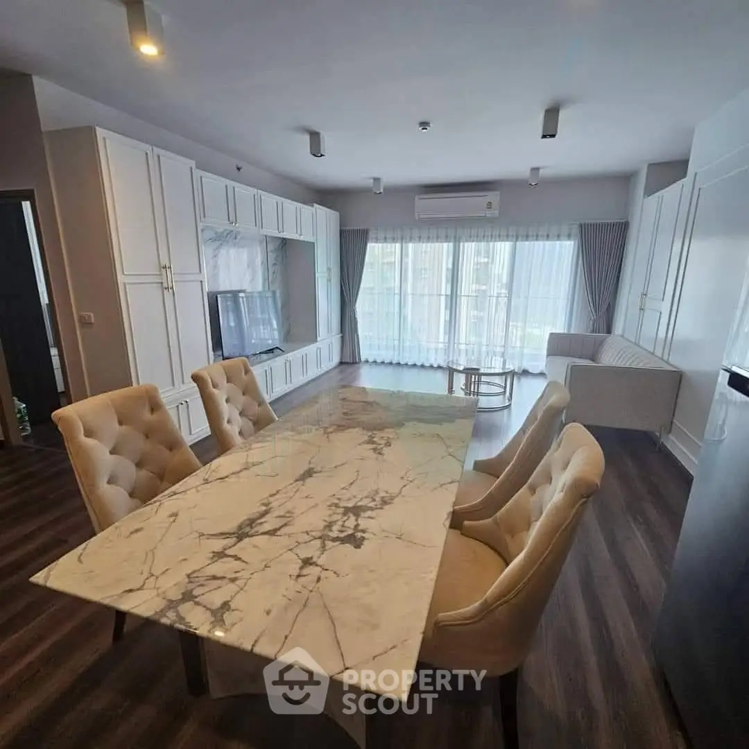 Spacious modern living room with elegant marble dining table and large windows for natural light.