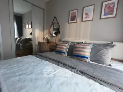 Cozy bedroom with stylish decor and plush bedding, featuring a mirror and framed art on the wall.