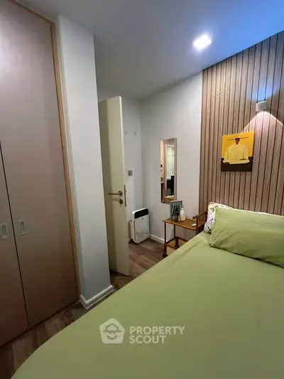 Cozy bedroom with modern decor and green bedding in stylish apartment.